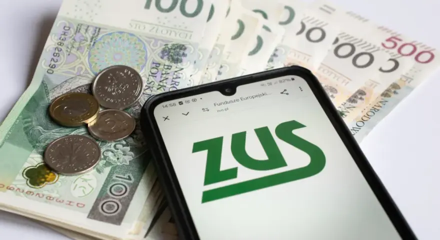 Na ekranie telefonu widnieje logo ZUS. Obok leżą polskie banknoty i monety. To może być druk z15 związany z finansami.