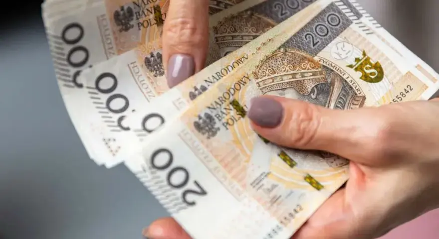 Dłoń trzyma stos banknotów 200 zł. To może być pożyczka od rodziny na nieprzewidziane wydatki.