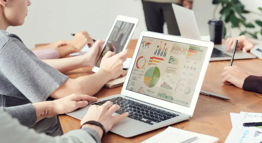 Analityk finansowy pracuje nad raportem na laptopie, analizując wykresy i dane.