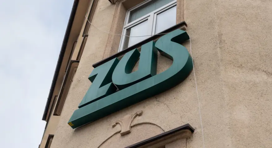 Zielone logo ZUS na budynku. To miejsce, gdzie można załatwić sprawy związane z ubezpieczeniem chorobowym.