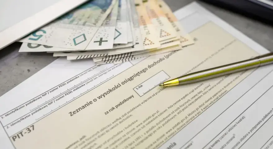 Pieniądze i formularz PIT-37. Zastanawiasz się, jaka jest kwota wolna od podatku? Długopis czeka na wypełnienie zeznania.