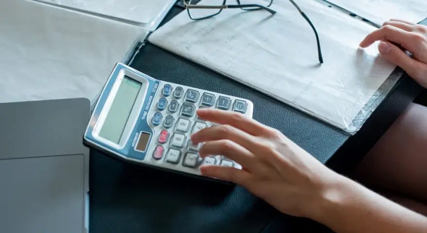 Ręce liczą na kalkulatorze dokumenty, analizując umowę zlecenie i potencjalne problemy z komornikiem.
