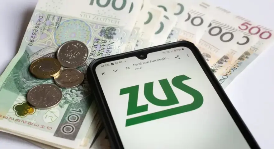 Złotówki i monety na tle ekranu telefonu z logo ZUS. To może być obrazek o okresowa emerytura kapitałowa.