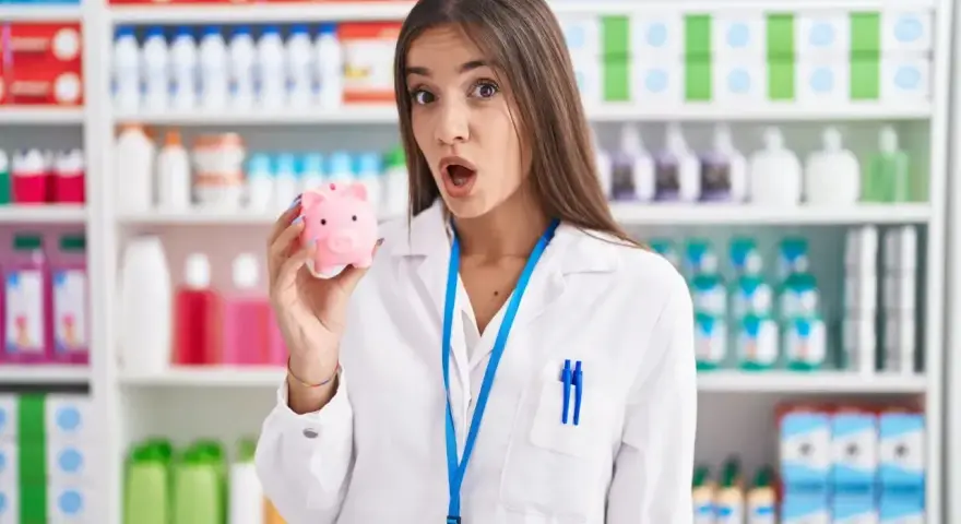 Zaskoczona farmaceutka trzyma skarbonkę, zastanawiając się, ile zarabia technik farmacji.