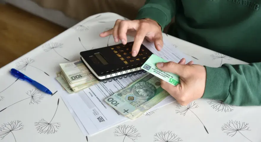 Ręce liczą pieniądze i dokumenty ZUS, przygotowując się do złożenia wniosku o rentę chorobową.