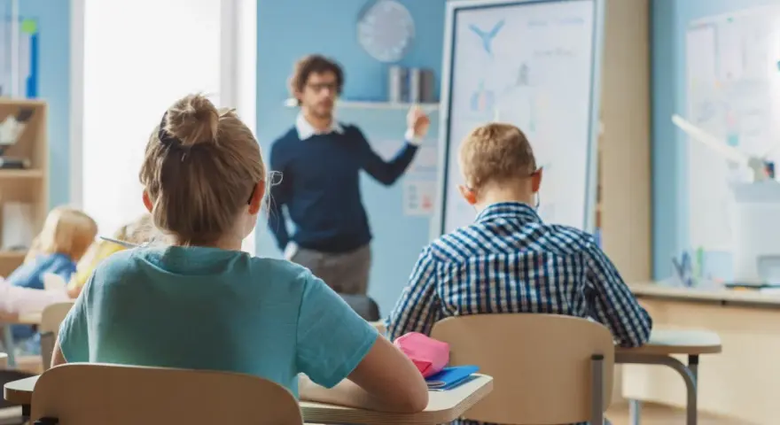 Nauczyciel tłumaczy lekcję, a uczniowie słuchają. Ciekawe, ile zarabia nauczyciel za taką pracę?