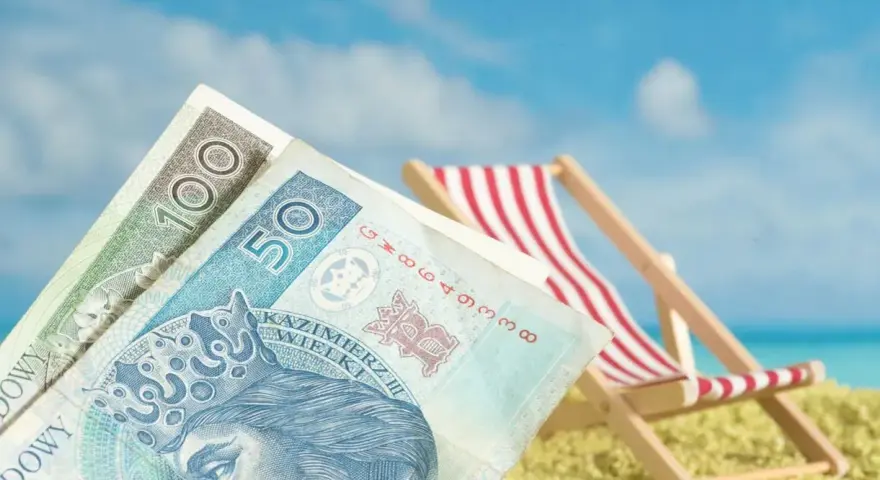 Pieniądze na plaży, leżak i błękitne niebo. To idealne połączenie, by cieszyć się zasłużonym świadczeniem urlopowym.