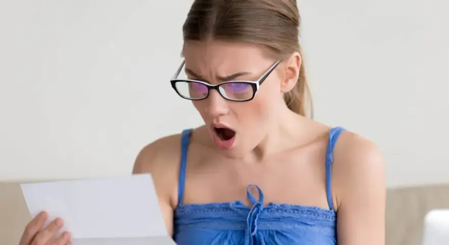 Zaskoczona kobieta w okularach czyta dokument. Czy to wypowiedzenie umowy zlecenia?