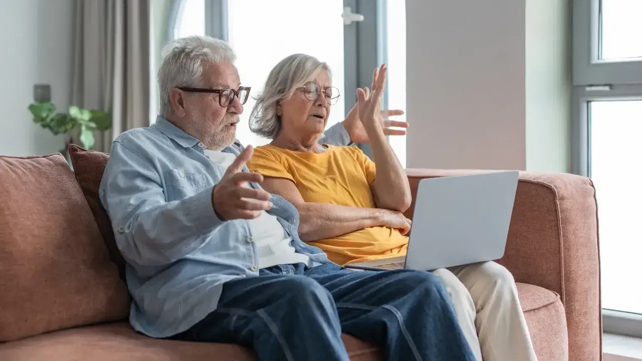 Zaskoczeni seniorzy patrzą na laptopa, dyskutując o tym, kiedy ZUS robi przelewy.