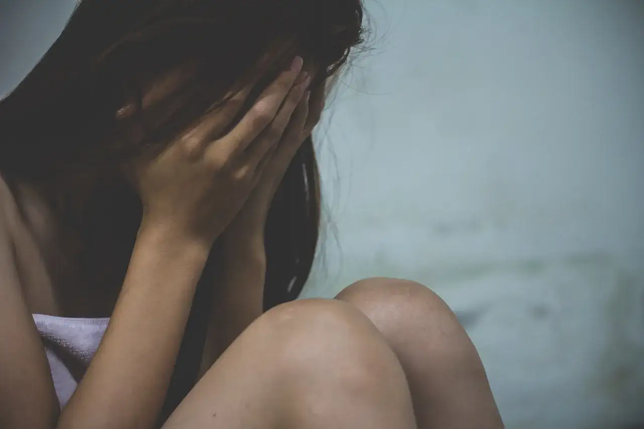 Osoba ukrywająca twarz w dłoniach, zmartwiona. Może to symbolizować trudności związane z wypowiedzeniem umowy o pracę a zwolnieniem lekarskim od psychiatry.