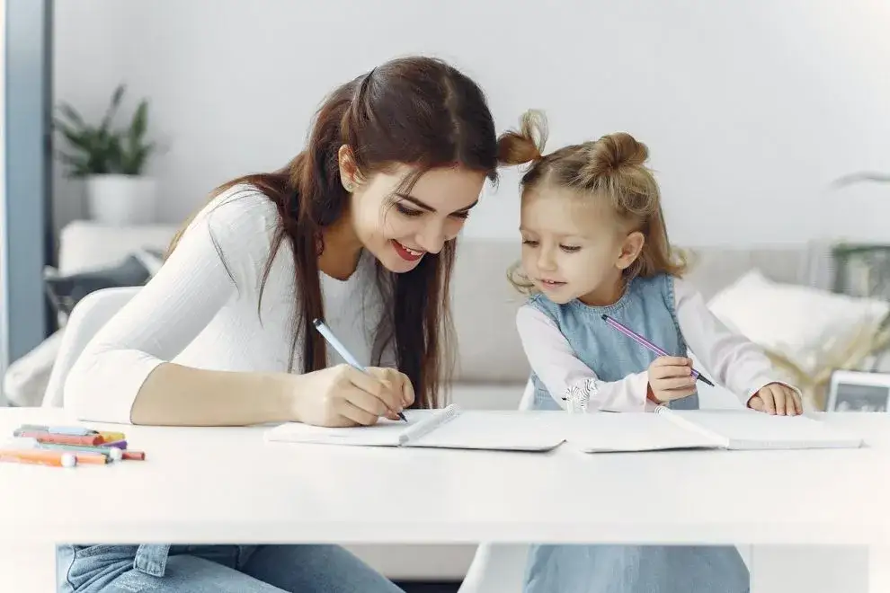 Rodzic z dzieckiem uczącym się w domu, uśmiechnięci, nowoczesna edukacja