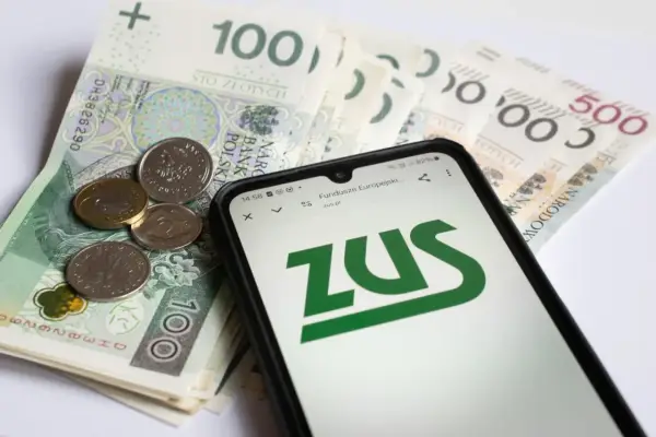 Na ekranie telefonu widnieje logo ZUS. Obok leżą polskie banknoty i monety. To może być druk z15 związany z finansami.