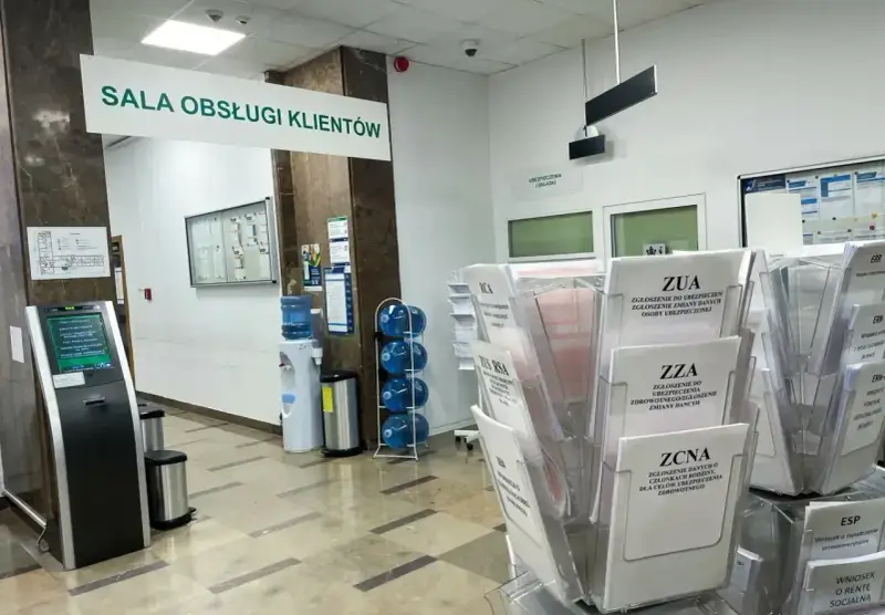 Sala obsługi klienta z terminalem, dystrybutorem wody i stojakami z formularzami ZUS, np. ZUA, ZZA, ZCNA. rp7.
