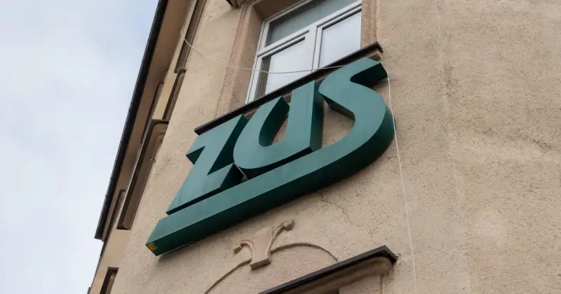 Zielone logo ZUS na budynku. To miejsce, gdzie można załatwić sprawy związane z ubezpieczeniem chorobowym.