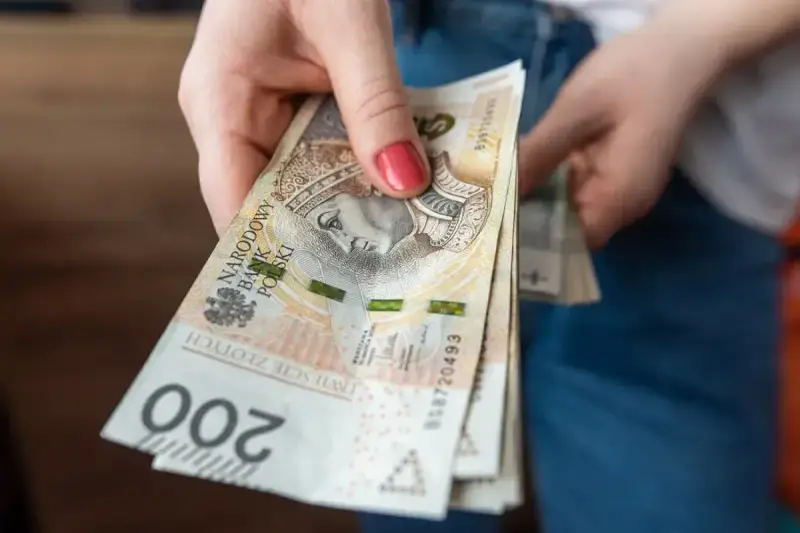 Dłoń trzyma stos banknotów 200 zł. Czekamy na przelew, kiedy ZUS robi przelewy, to zawsze radość.
